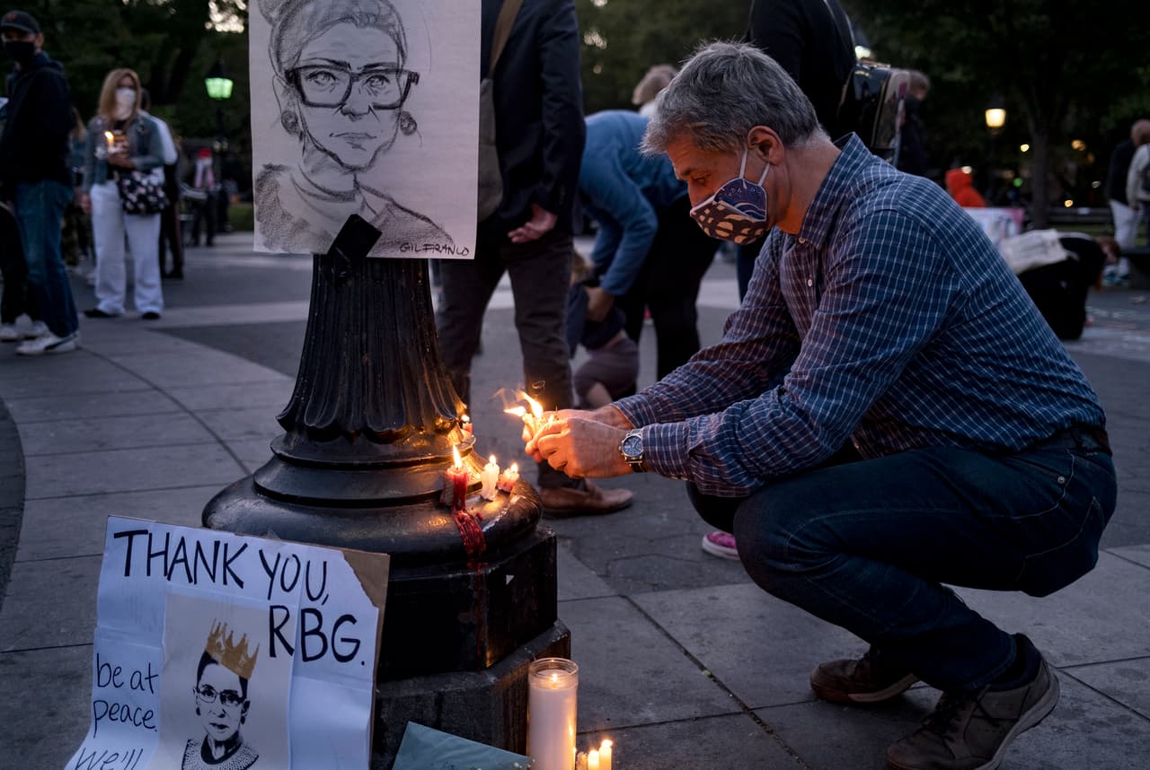 Roland Levin de Nueva York coloca velas cerca de un dibujo de la Juez Ruth Bader Ginsburg mientras él y otros se reunieron en Washington Square Park.