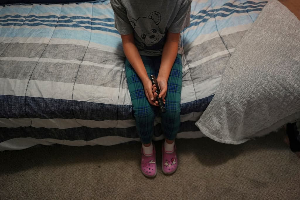 Una niña de 9 de años con estatus protegido temporal, o TPS, que nació en Venezuela, pero que sólo habla inglés con fluidez y que está en el programa de alumnos con talento en su escuela, ve la televisión en el apartamento de su familia, el sábado 5 de abril de 2025, en Doral de Florida. (AP Foto/Rebecca Blackwell)