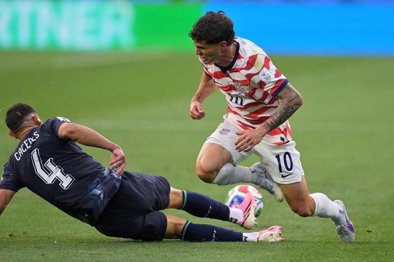 El paraguayo Juan José Cáceres (4) disputa el balón con el estadounidense Christian Pulisic.