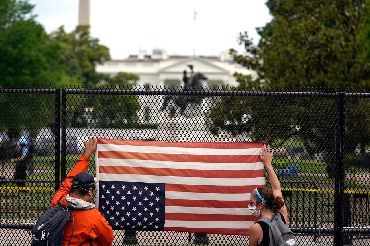 Un par de manifestantes sostienen una bandera estadounidense boca abajo frente al Parque Lafayette -cerca de la Casa Blanca- en Washingon D.C.