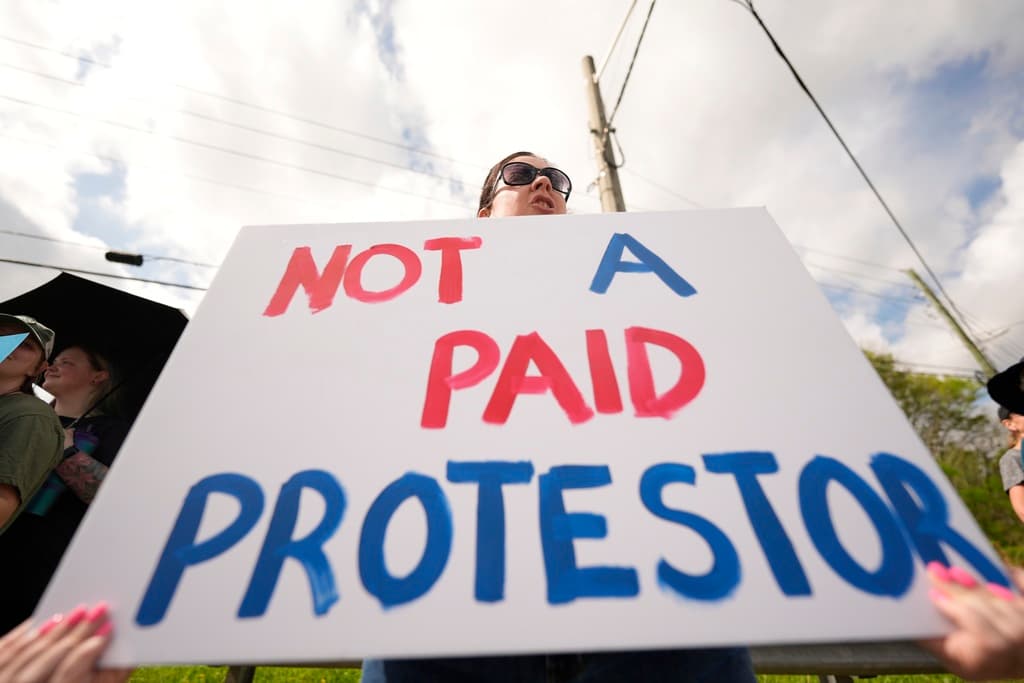 <b>Defensa de derechos sociales y humanos</b>: En la imagen, un manifestante porta una pancarta en la que se lee "No soy protestante pagado". Las protestas denunciaron la deportación de inmigrantes, la reducción de protecciones para personas trans y los recortes a programas federales de salud. (Washington DC)