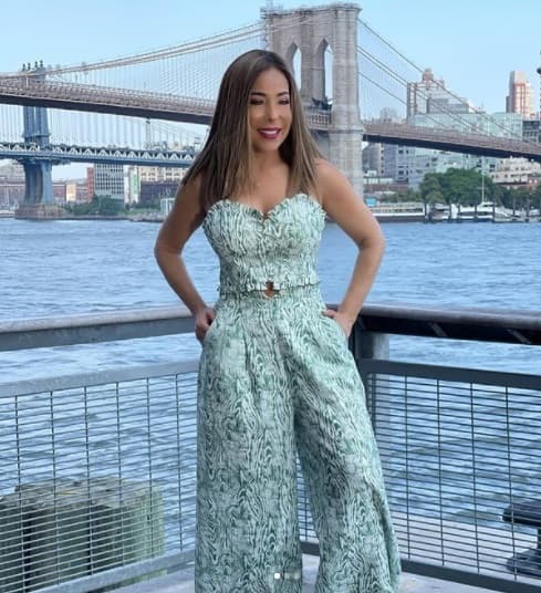 Esta bella postal resalta la belleza del paisaje urbano, con la de la periodista con un traje de dos piezas en colores blancos y azules, se trata de un top y un pantalón amplio a juego.