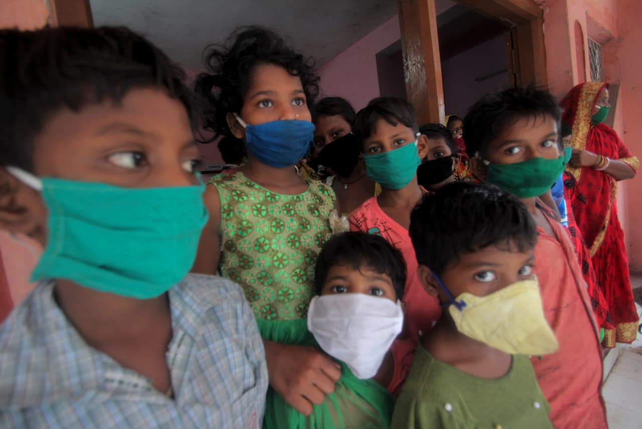 Niños evacuados con máscaras como precaución contra la propagación del coronavirus se encuentran en un campamento de socorro en Paradeep, en la costa de la Bahía de Bengala en Orissa, India.