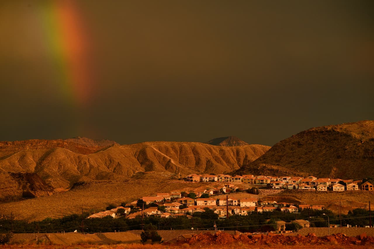 La sequía del oeste se refleja en la represa que alimenta de agua partes de Arizona, Nevada y California. Un arco iris brilla detrás de las casas en una ladera durante la sequía occidental el 20 de julio de 2021 en St. George, Utah. - Se propone una tubería de agua de aproximadamente 140 millas para llevar agua adicional desde el río Colorado y el lago Powell en Arizona a las comunidades en el sur de Utah.