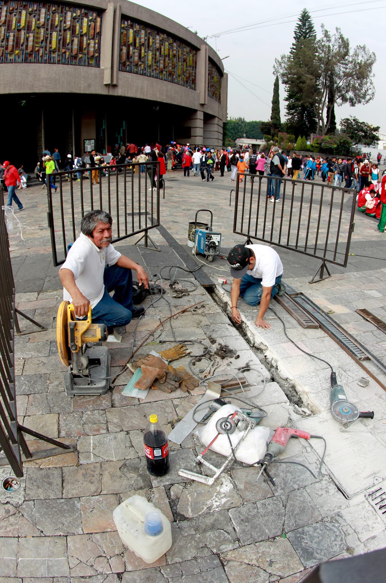 Una pareja de trabajadores arreglan parte del piso dañado de la Basílica de Guadalupe.