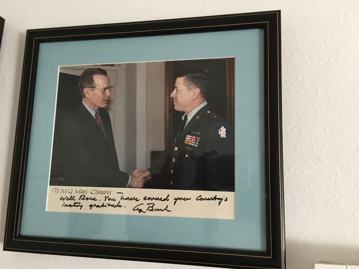Un foto de Cisneros con presidente George H Bush. "Te has ganado la gratitud duradera de tu país", dice esta foto firmada del gen Marc Cisneros con el presidente George H Bush. Se encuentra en un lugar destacado en la oficina central de Cisneros en Corpus Christi, Texas. Cisneros proviene de una familia con una historia de servicio público. Su tío abuelo, J.T. Canales, fue un destacado líder político mexicano-estadounidense de Texas, que ayudó a fundar la Liga de Ciudadanos Latinoamericanos Unidos (LULAC). Después de retirarse del ejército, fue nombrado presidente de Texas A&M University-Kingsville.