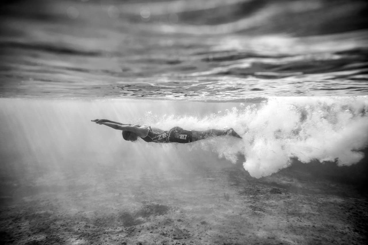 En blanco y negro, se ve la imagen subacuática de una atleta en el Mundial Juvenil de Triatlón en el el Parque Fonatur de Triatlón en Cozumel, Mexico. Calma en medio de la competencia.