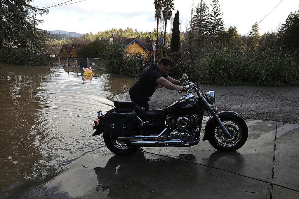 Hombre empuja su moto en Guerneville después de las inundaciones de esta semana.