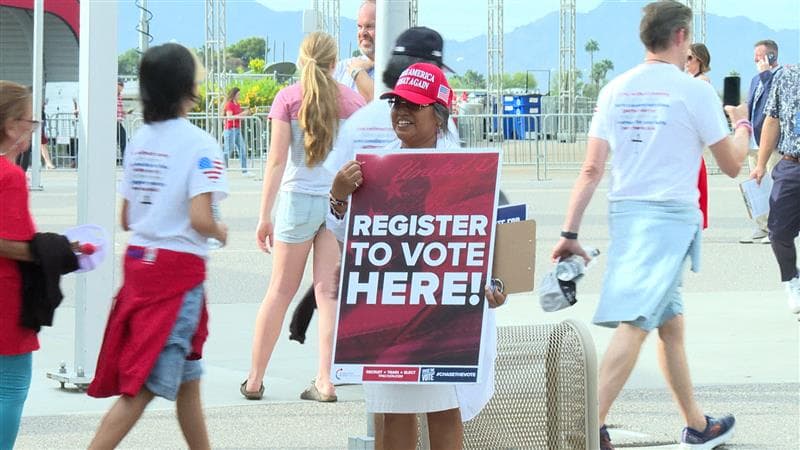 Afuera, personas invitando a los asistentes y a quienes se encontraban en la zona, a 
<b>registrarse para votar</b>.