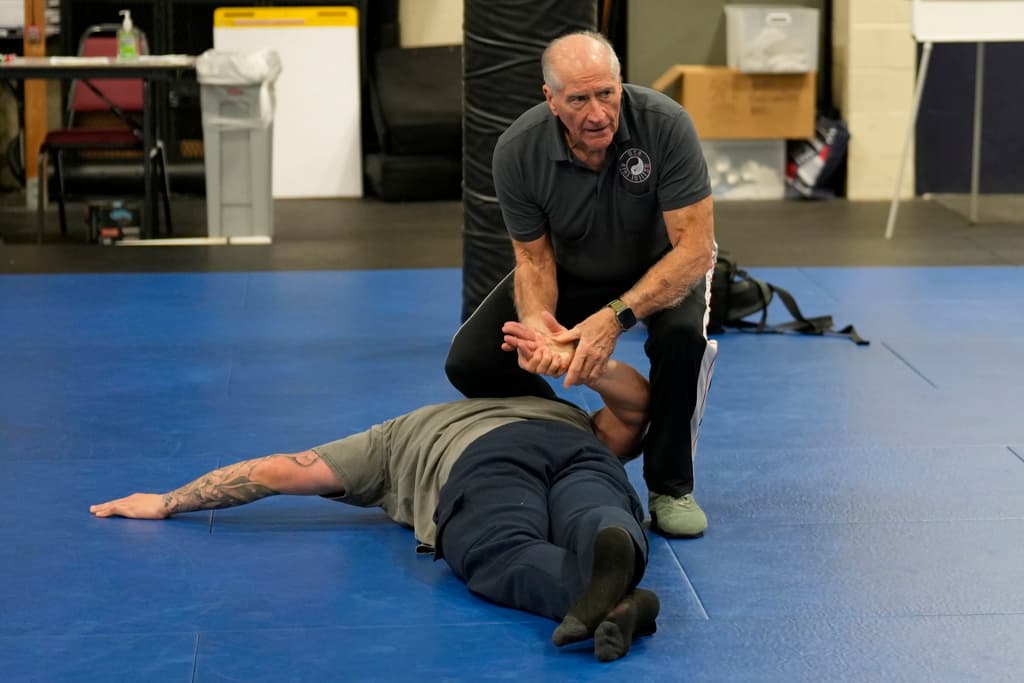 El instructor Dave Rose demuestra una posición boca abajo esposada a un estudiante durante un curso de Instructor de Arresto y Control en Sacramento, California, el jueves 18 de enero de 2024. Rose ha entrenado a generaciones de oficiales en el sentido de que la sujeción boca abajo es segura. Sus alumnos son instructores que llevan su formación a sus departamentos.
