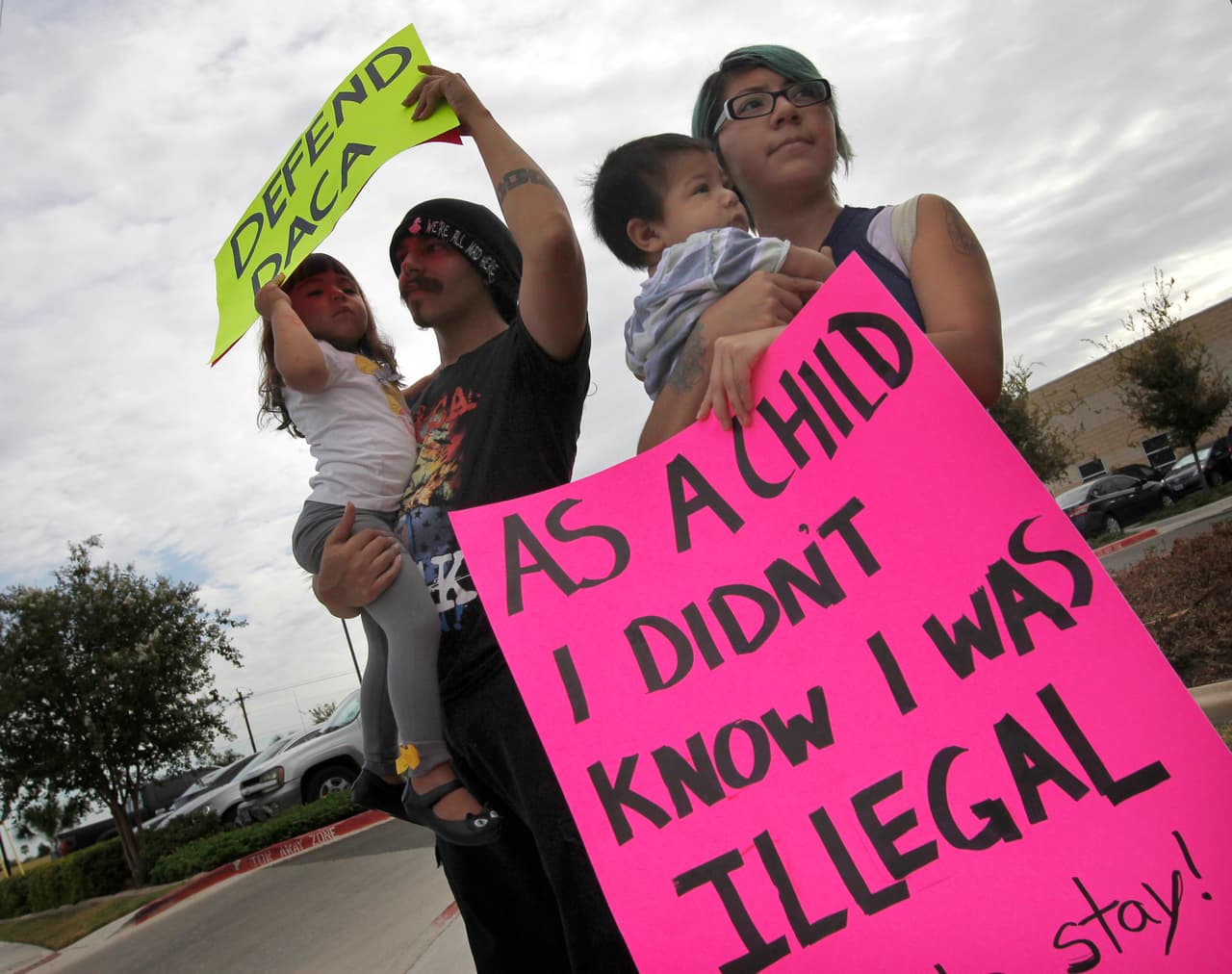 Los esposos Kathia Ramírez y Randy Salinas protestan junto a sus hijos frente a la oficina del fiscal general en el estado en Pharr, Texas.