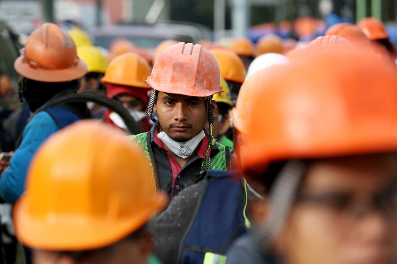 El rostro de un voluntario se destaca en la multitud de cascos naranja, cerca de uno de los edificios colapsados en la ciudad.