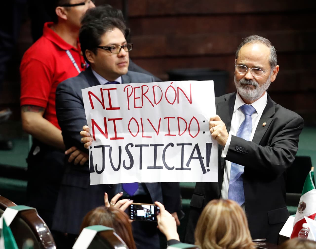 El legislador Gustavo Madero sostiene un cartel que dice "Ni perdón, ni olvido ¡Justicia!"
