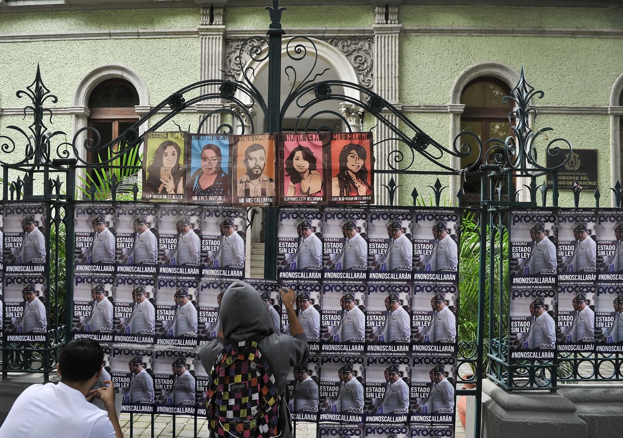 Activistas pegan carteles de periodistas muertos en Veracruz.