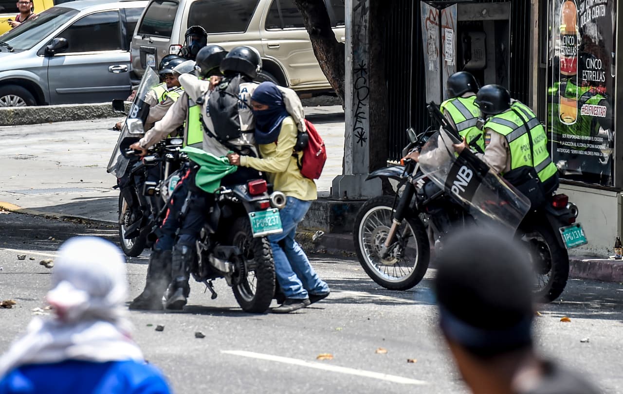 Una pareja de policías nacionales trata de llevarse a un manifestante detenido.