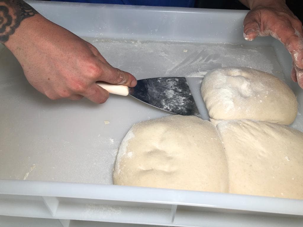 Después que la masa crece, la corta en varios pedazos, con lo cuales hace las bolas para realizar la base de la pizza.