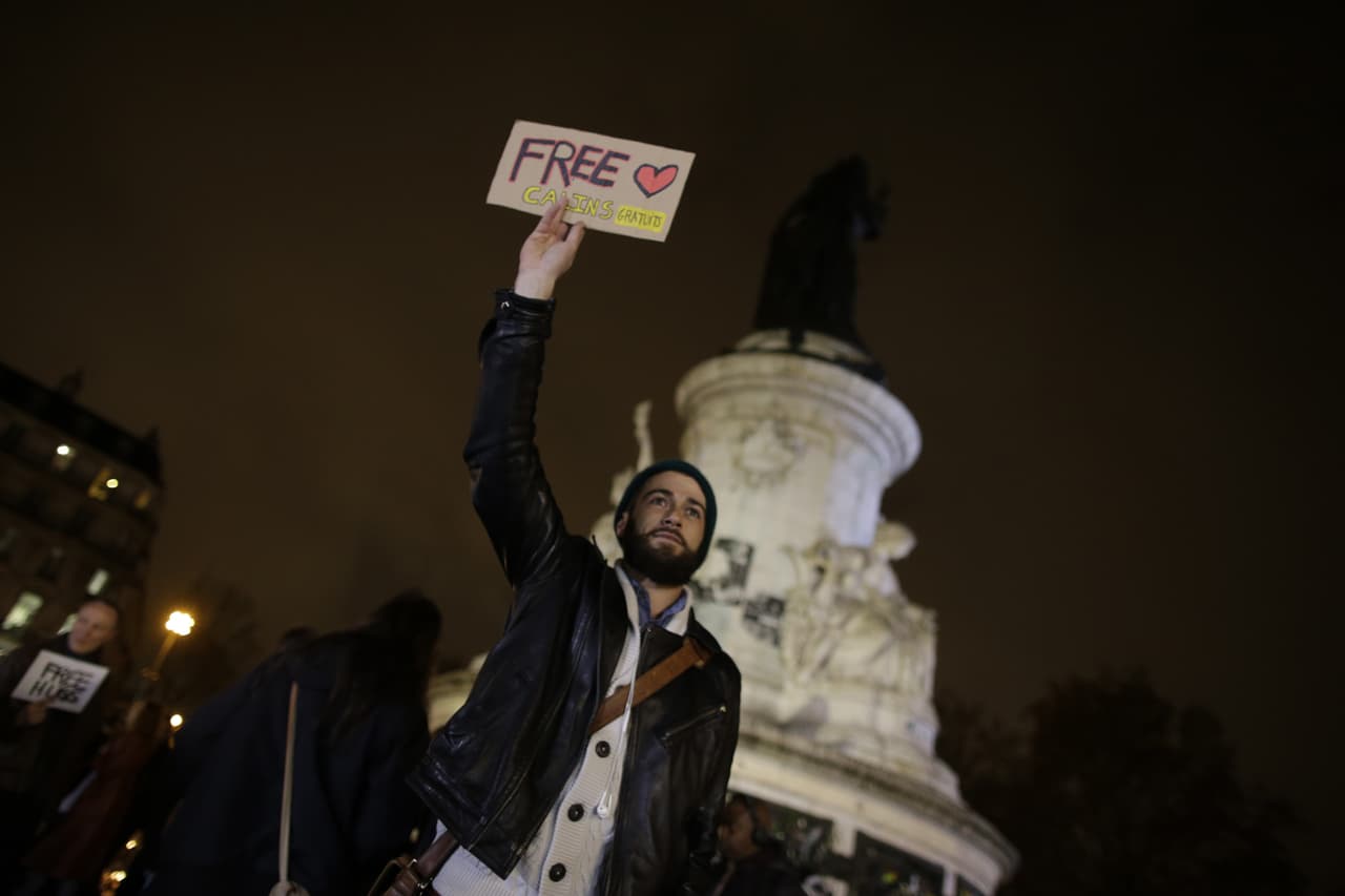 Un hombre sostiene un cartel que dice: "Free Hug's en un monumento improvisado para las víctimas.