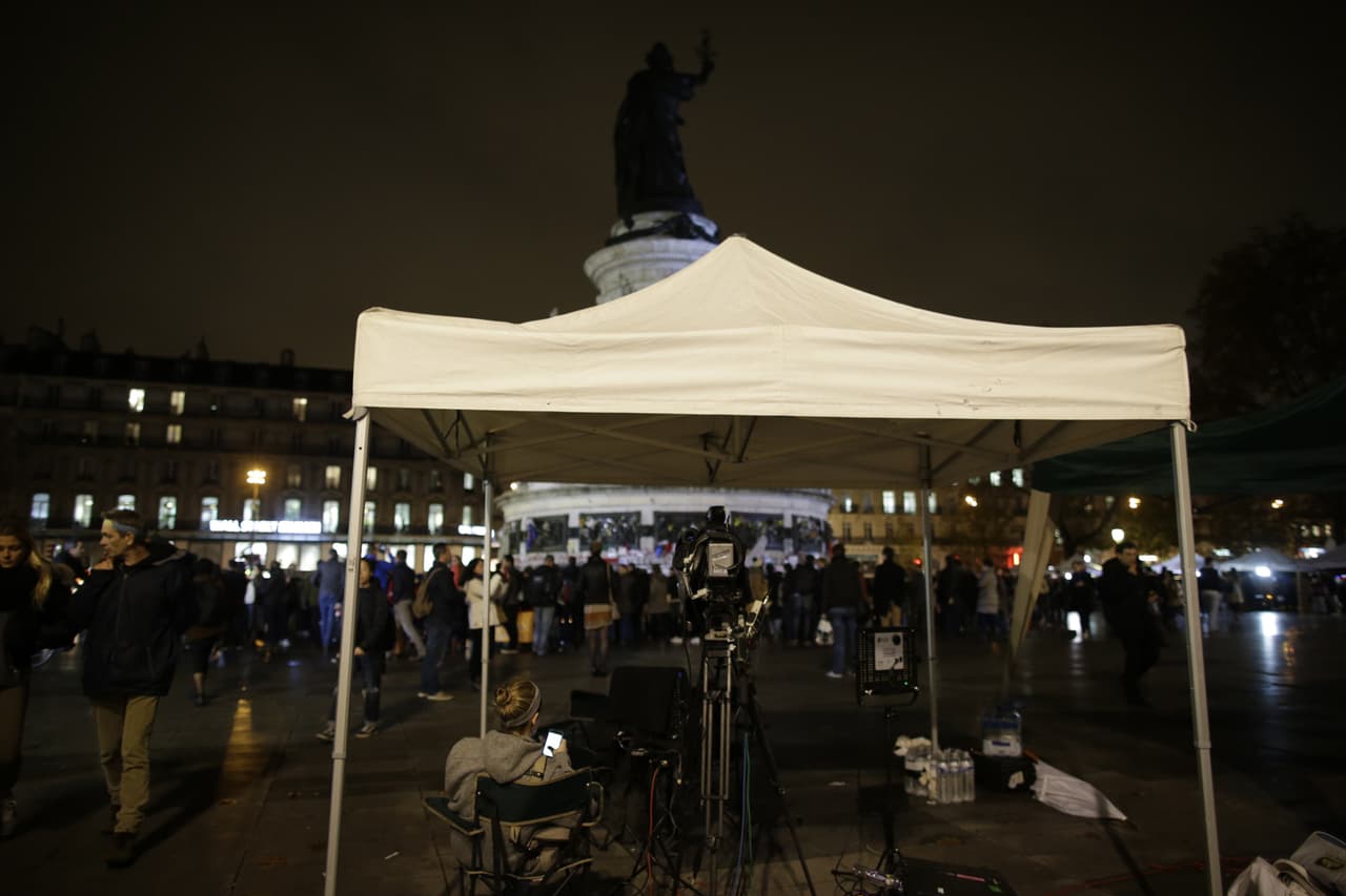 Una mujer espera cerca de las cámaras en un monumento improvisado.