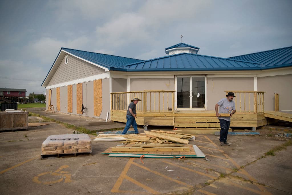 Dos personas trabajan en la protección de un edificio que protegieron, en Sabine Pass, Texas.