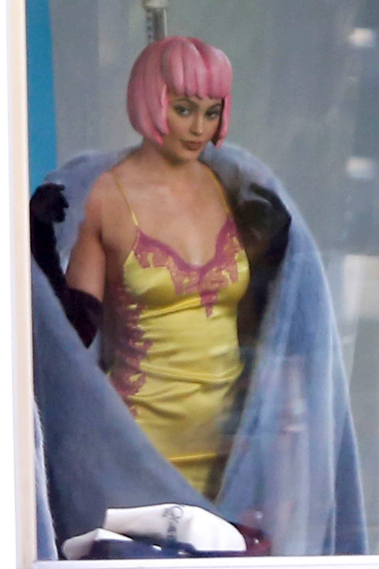 Con una peluca de plástico rosa.