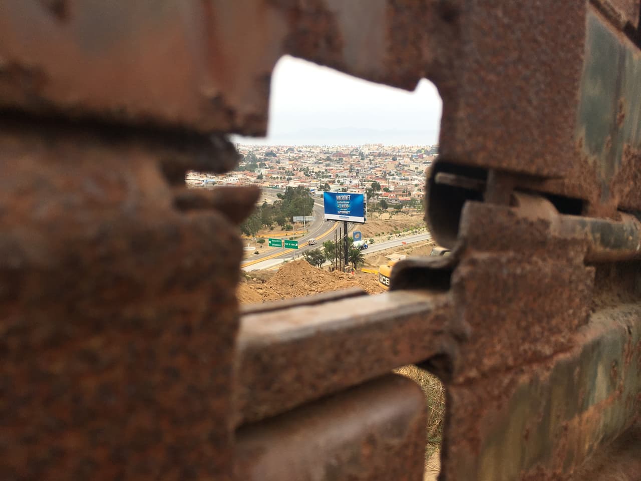 Un cartel publicitario en Tijuana se observa a través del viejo cerco fronterizo de Estados Unidos.