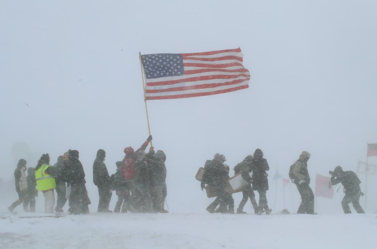 CANNON BALL, ND - DECEMBER 05: Despite blizzard conditions, military veterans march in support of the "water protectors" at Oceti Sakowin Camp on the edge of the Standing Rock Sioux Reservation on December 5, 2016 outside Cannon Ball, North Dakota. Over the weekend a large group of military veterans joined native Americans and activists from around the country who have been at the camp for several months trying to halt the construction of the Dakota Access Pipeline. Yesterday the US Army Corps of Engineers announced that it will not grant an easement for the pipeline to cross under a lake on the Sioux Tribes Standing Rock reservation. The proposed 1,172-mile-long pipeline would transport oil from the North Dakota Bakken region through South Dakota, Iowa and into Illinois. (Photo by Scott Olson/Getty Images)