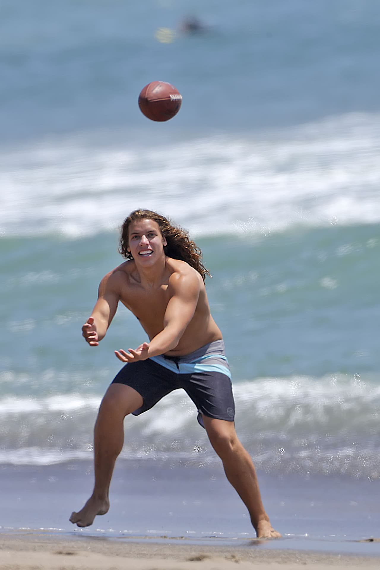 Joseph Baena, el hijo latino de Arnold, lanza un balón en la playa.