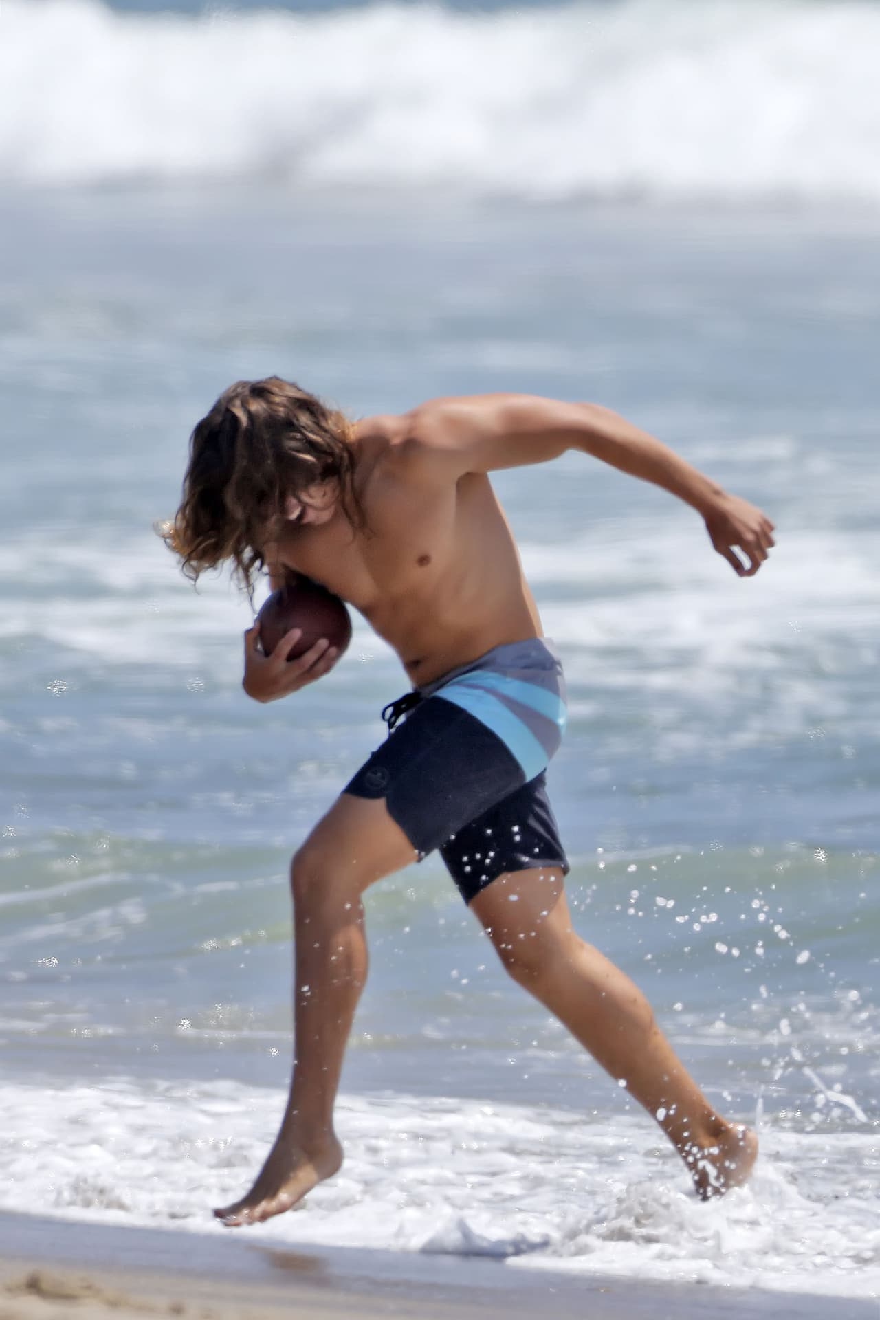Joseph Baena, el hijo latino de Arnold, lanza un balón en la playa.