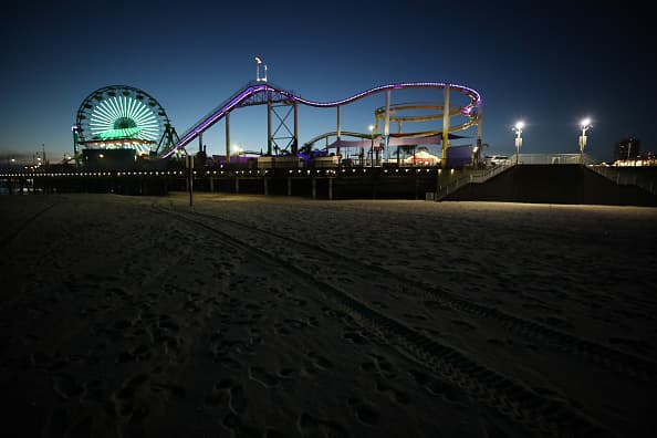 Las luces siguen iluminando al popular muelle de Santa Monica pese al desolado destino turístico.
<br>
