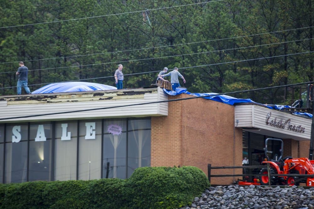 Los trabajadores de esta tienda, Cahaba Tractor, trabajan para proteger el techo dañado del negocio después de ser golpeado por un tornado en un día de clima severo, en Pelham, Alabama.