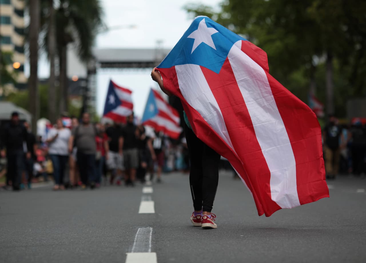 Un manifestante cubierto por la bandera puertorriqueña. La isla está sumida en una recesión económica desde 2006 y lleva a cuestas un déficit de unos 50,000 millones de dólares. (Reuters)