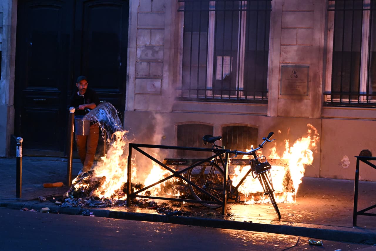Un hombre intenta apagar un incendio durante los enfrentamientos entre manifestantes y policías en París, el domingo 18 de octubre de 2026.