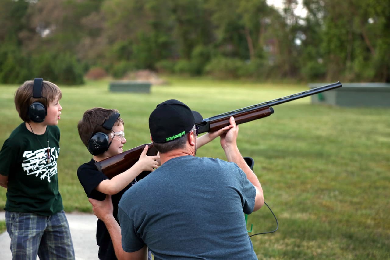 Nate, centro izquierda, el hijo de la esposa de Berwick, derecha, dispara un rifle en un evento del Club de Armas de Pine Valley, en Berlin, Nueva Jersey, en el sur rural del estado, el 26 de mayo de 2016.