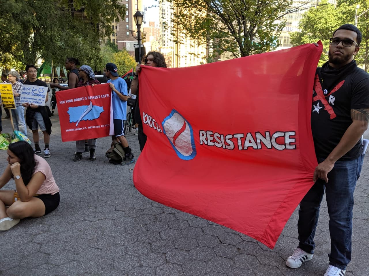 Manifestante sostiene una manta que dice: "Resistencia Boricua"