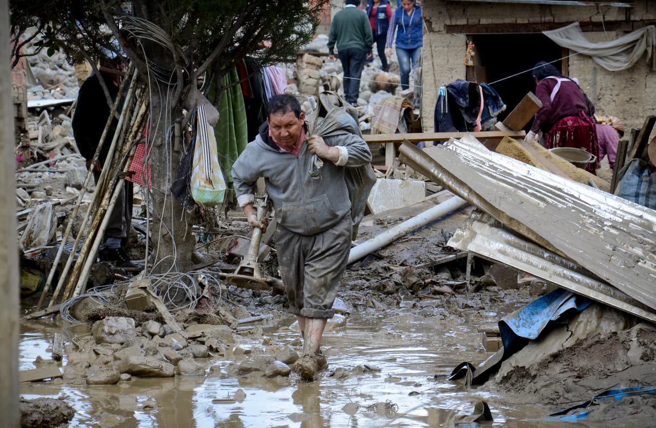 Un residente de Cochabamba rescata sus pertenecias de su casa afectada por el lodo. El desborde del río Taquiña arrastró todo lo que encontró a su paso, mientras que los vecinos relataron que la corriente y el lodo también afectó las conexiones de agua y gas doméstico de la zona.