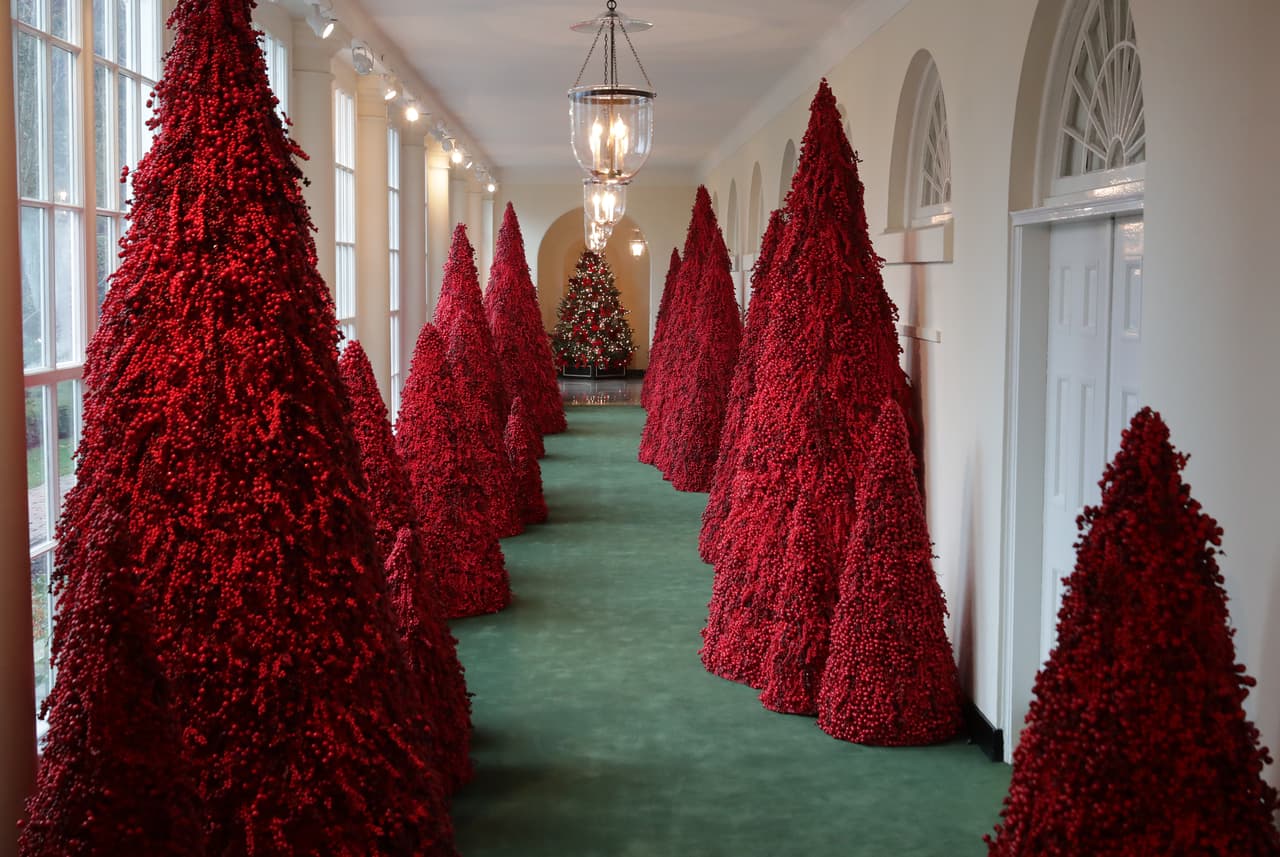 Más de 40 árboles de color rojo se alinearon en la Columnata Este, que lleva hacia el Salón Jardín Este, decorada con la tarjeta navideña de la primera familia.