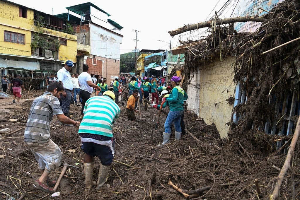 Los residentes ayudan a los rescatistas a desenterrar el lodo de las casas destruidas mientras buscan víctimas o sobrevivientes de un deslizamiento de tierra que dejó 22 muertos y 52 desaparecidos, así como decenas de casas destruidas durante las fuertes lluvias en Tejerias, estado de Aragua, Venezuela, el 9 de marzo de 2022.