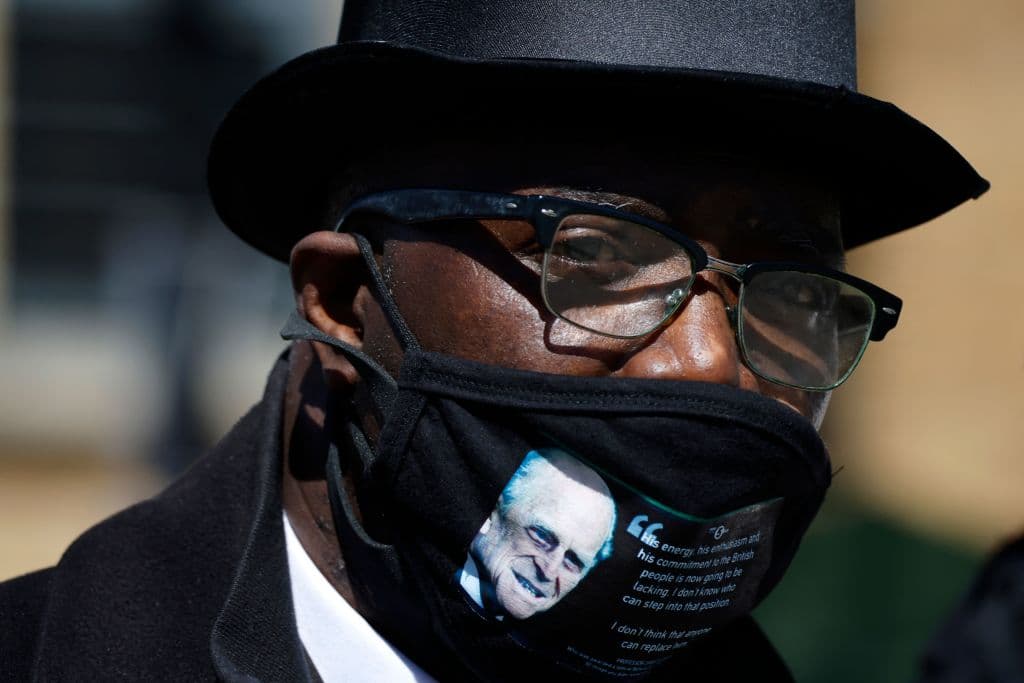Un hombre con una mascarilla negra con la foto de Felipe presenta sus respetos a la memoria del esposo de la reina en Windsor.