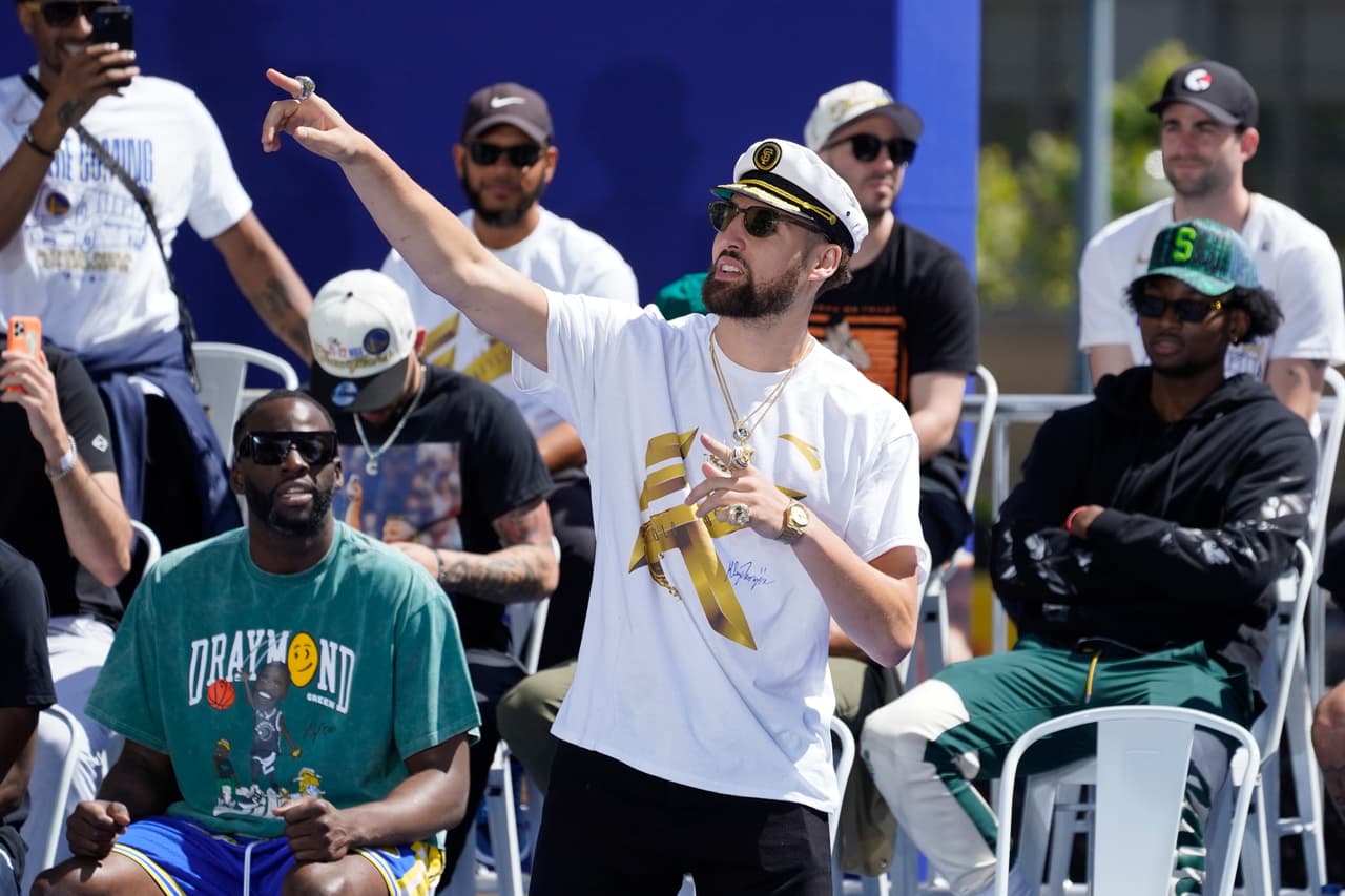 Klay Thompson, de los Golden State Warriors, gesticula en el escenario mientras Draymond Green mira a la izquierda antes del inicio del desfile por el campeonato de la NBA en San Francisco, el lunes 20 de junio de 2022. (AP Photo/Eric Risberg)