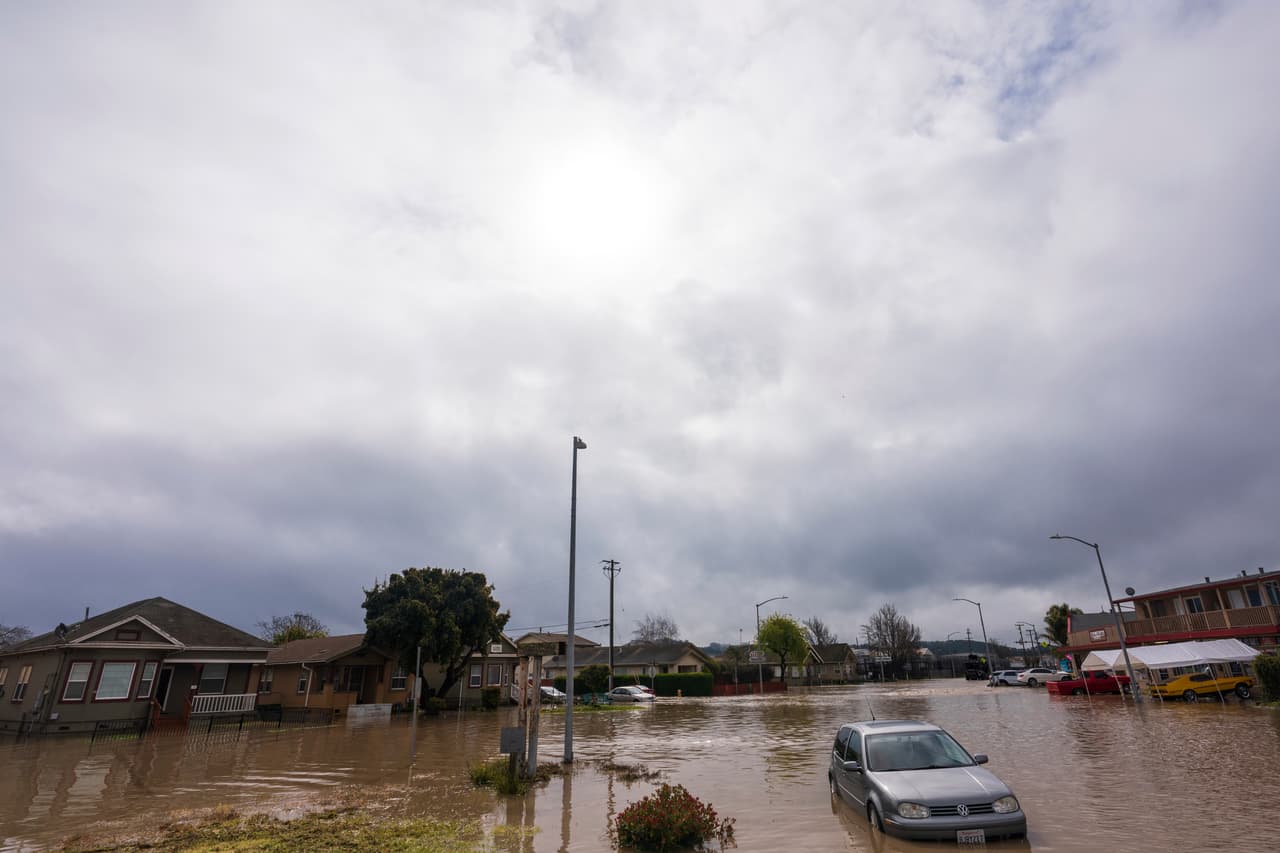 Las nubes destacan en el cielo mientras un automóvil está sumergido en las aguas de la inundación en Watsonville, California, el sábado 11 de marzo de 2023.