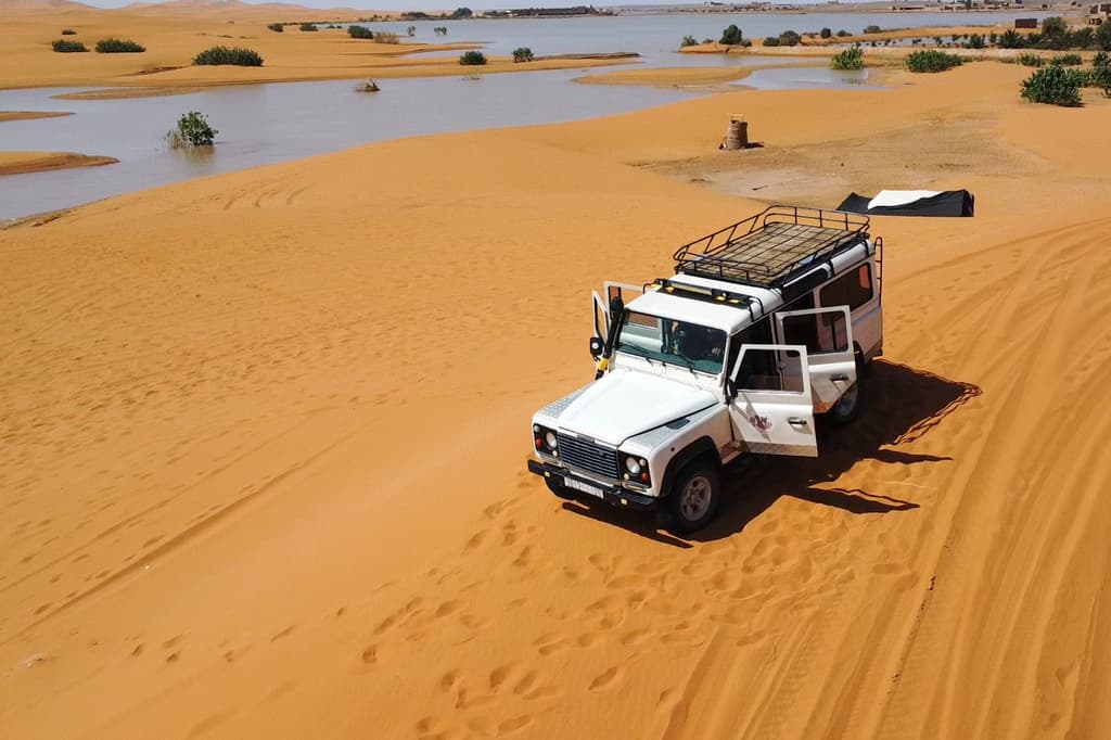 Un vehículo transporta turistas por las dunas de arena junto a un lago provocado por las fuertes lluvias en la ciudad desértica de Merzouga, cerca de Rachidia, sureste de Marruecos, miércoles 2 de octubre de 2024.