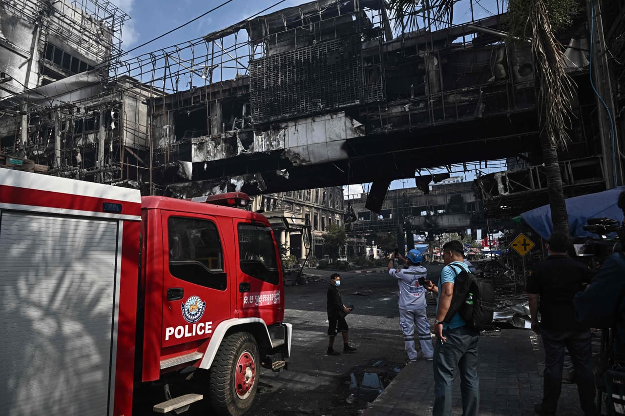 Varias personas toman fotografías junto a una parte destruida del hotel-casino Grand Diamond City tras el incendio.