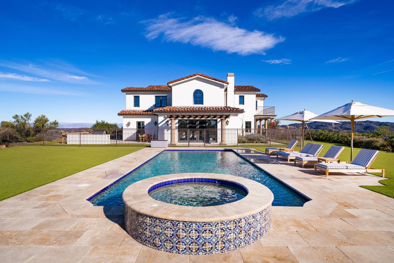 En el exterior, hay un gran patio con un espacio que cuenta con parrillas instaladas, una piscina, spa y un pozo para hacer fogatas.