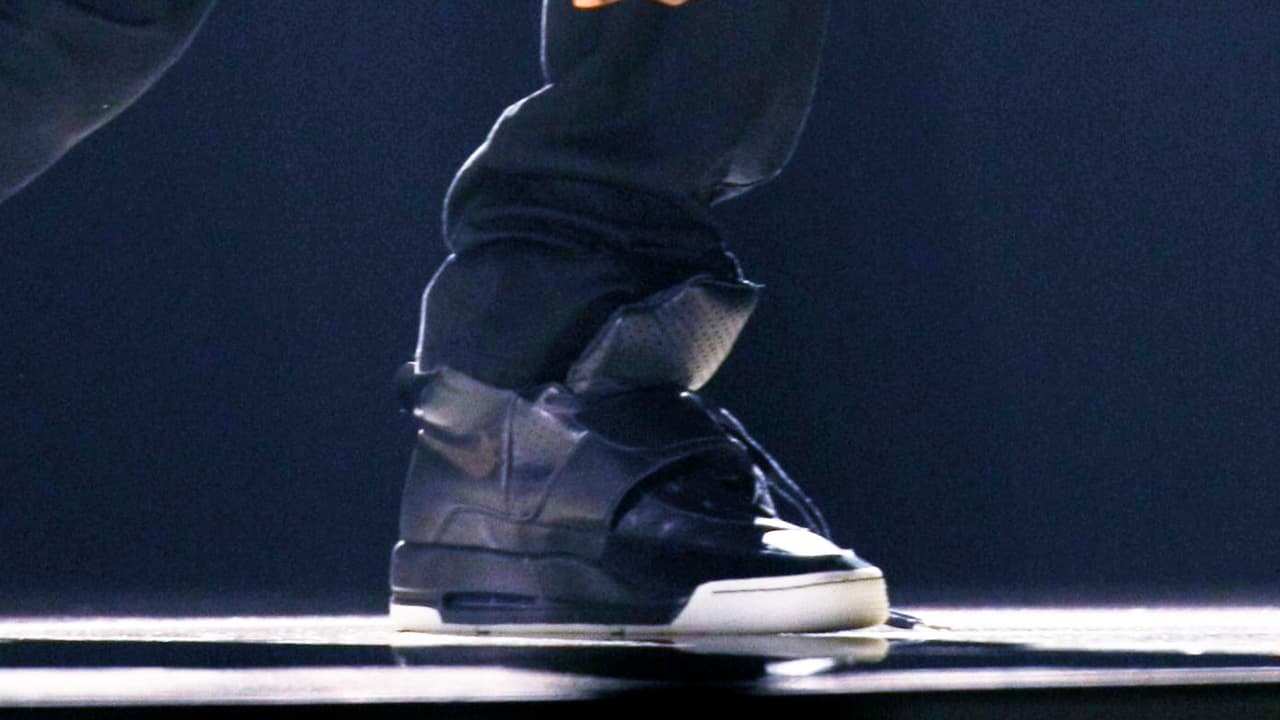 Los tenis están hechos en cuero negro suave con detalles perforados en la parte superior.