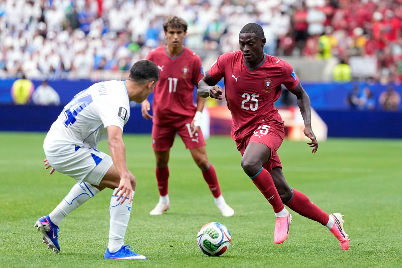 Nuno Mendes, de Portugal, corre con el balón hacia Behruzjon Karimov, de Uzbekistán (izquierda), durante el partido de fútbol del Grupo K de la Copa Mundial entre Portugal y Uzbekistán