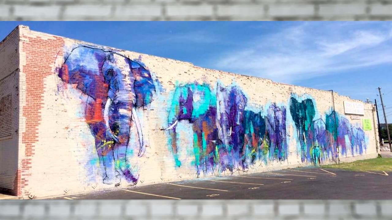 <b>Una estampida de elefantes azules</b> en el corazón de la ciudad de Dallas. Este increíble mural urbano es del artista de raíces hispanas Adrián Torres. La manada de elefantes cubre gran parte de la fachada de un edificio. 
<br>📍 Lo puedes encontrar en 
<b>3601 Main Street</b>.