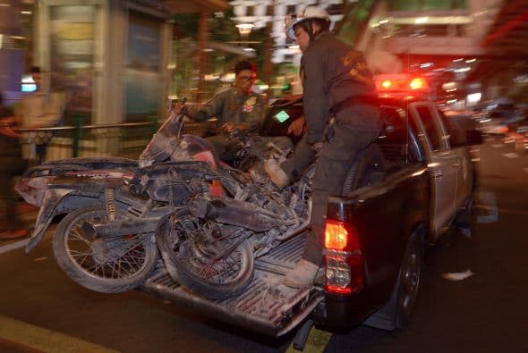 Trabajadores transportan motocicletas destruidas por la detonación.
