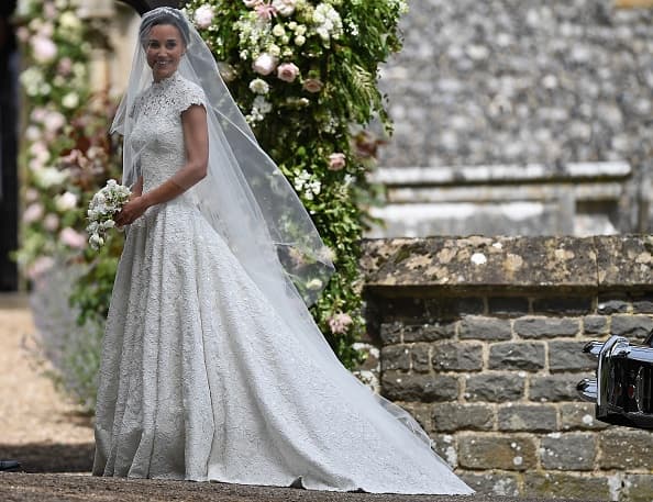 Pippa Middleton, como si fuera princesa, luce su vestido de novia entallado en el torso, con mangas cortas, al frente con cuello alto y en la espalda con un escote en forma de corazón, diseño de Giles Deacon. El velo fue creación de Stephen Jones y los zapatos son de Manolo Blahnik.
