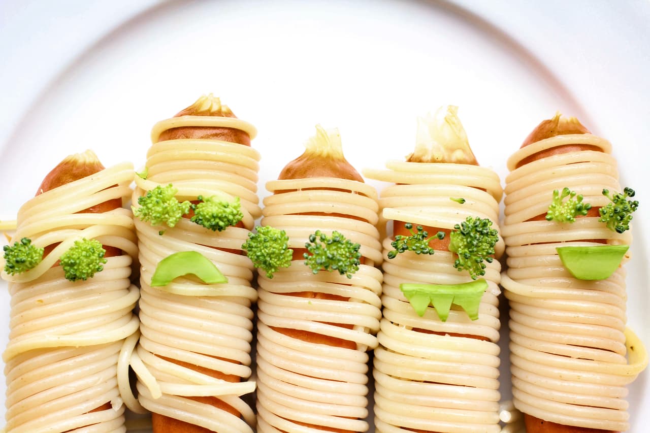 ¿Te atreverías a comer momias zombi? En vez de masa, puedes usar espagueti y trozos de vegetal para darles este 'look' monstruoso.