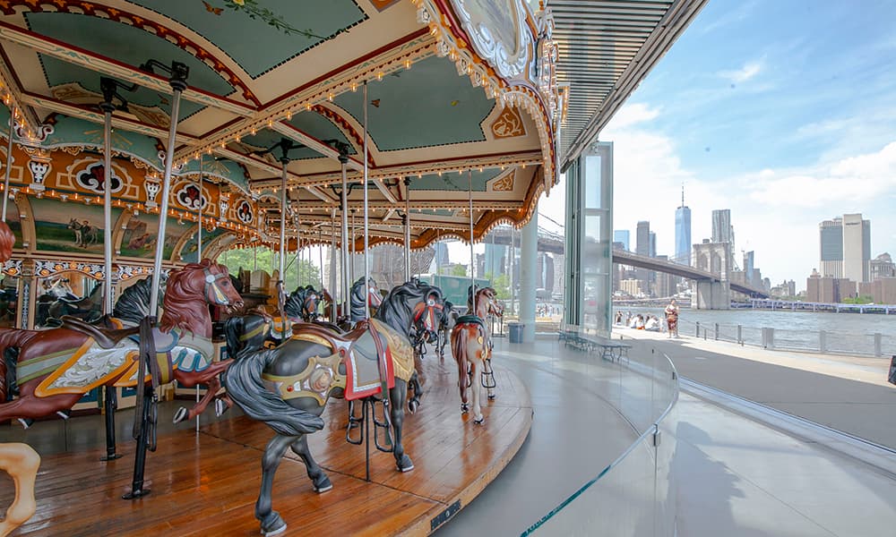 <b>Jane’s Carousel en Brooklyn</b>
<br>
<br>Sin duda este es uno de los carruseles más icónicos de la Ciudad.
<br>
<br>El Jane’s Carousel se encuentra bajo el puente de Brooklyn en el Brooklyn Bridge Park.
<br>
<br>
<b>Fue construido en 1922 y sus piezas de madera talladas fueron restauradas recientemente.</b>
<br>
<br>Se encuentra ubicado en una estructura de vidrio con una vista espectacular.
<br>
<br>Puedes
<b><a href="https://janescarousel.com/hours/" target="_blank"> revisar en este enlace su ubicación exacta y horarios. </a></b>
<br>
<br>
<br>